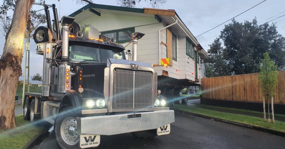 A relocated house being moved on a transporter